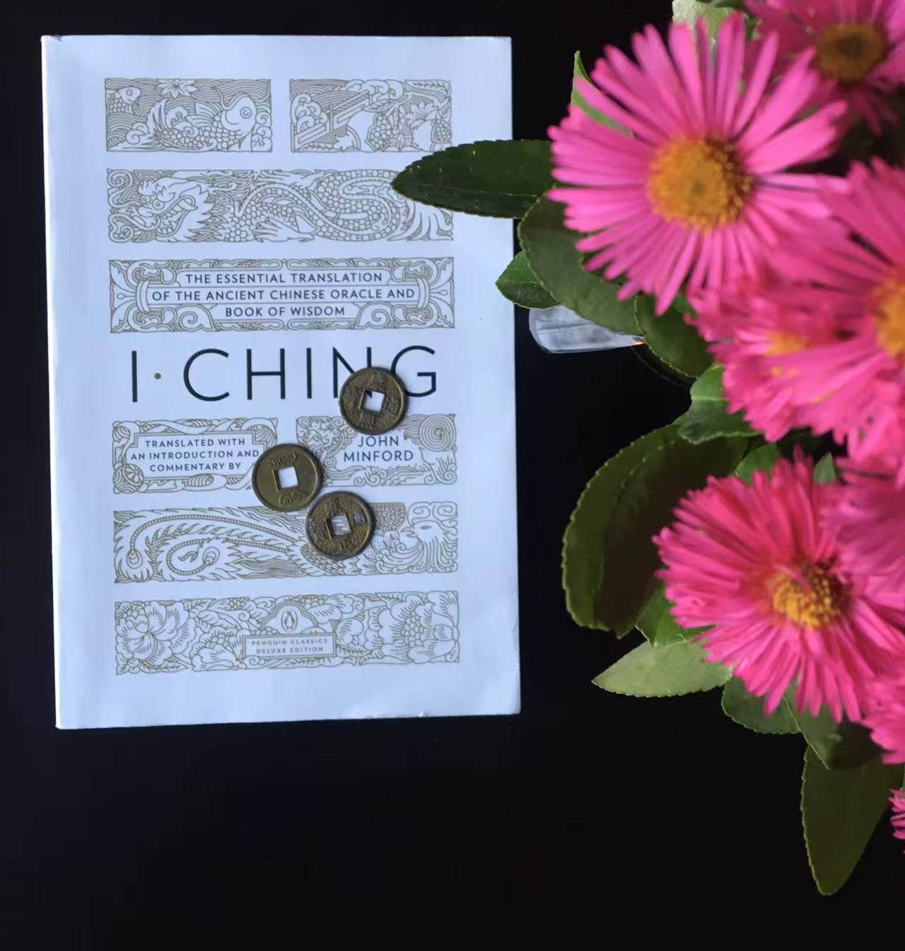 I Ching book with coins and flowers representing yin and yang balance in tarot reading